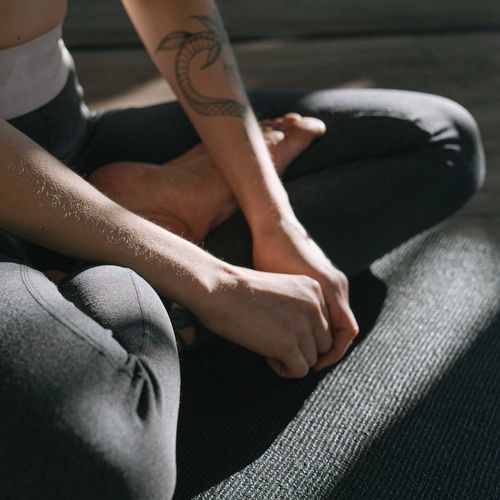 Person sitting in a calm cross-legged yoga pose indoors.